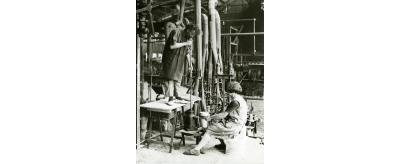 Un "gamin" tient le moule pendant le soufflage à la bouche d'une bouteille à la Verrerie d'Arleux, 1929