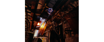 Souffleur de verre tenant la canne à bout de bras pour allonger le manchon par un mouvement de balancier dans la fosse à la Verrerie de Saint-Just, 1994