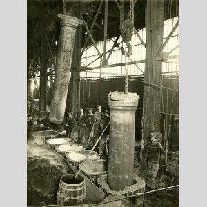 Démoulage de tuyaux de fonte coulés verticalement à l'usine de Pont-à-Mousson entre 1900 et 1932